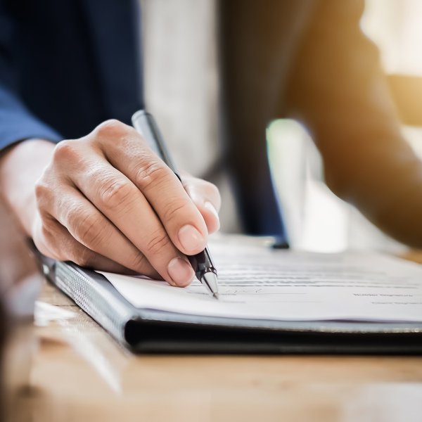 holding a pen to a document to sign